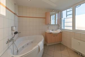 a white bathroom with a tub and a sink at Eisvogel Classic 217 in Granzow +21 photos
