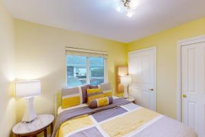 a bedroom with a bed with yellow walls and a window at Hip Nautic in Rockaway Beach