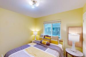 a bedroom with a bed with yellow walls and a window at Hip Nautic in Rockaway Beach