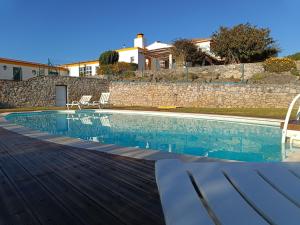 uma piscina com cadeiras e uma casa em Casal Serrano Charme e Tranquilidade em Reguengo Grande
