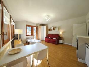 a kitchen and living room with a white table and chairs at Hostdomus - Casa Ariel in Cesana Torinese