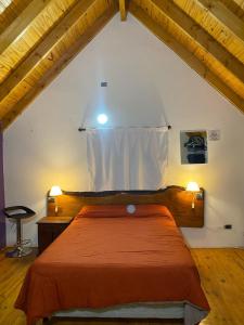 a bedroom with a orange bed in a attic at MAKAVIZA in Villa Pehuenia