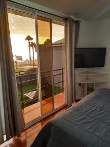 a bedroom with a bed and a balcony with a television at Hermosa casa frente a cavancha in Iquique