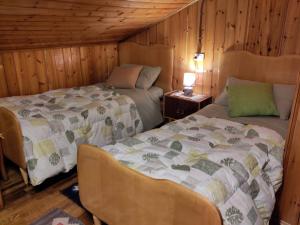 due letti in una stanza con pareti in legno di La cuccia di Elfo a Prali