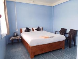 a bedroom with a bed with blue walls and two chairs at N D Phisha Homestay in Cherrapunji