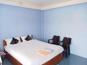 a bedroom with a bed with two chairs in it at N D Phisha Homestay in Cherrapunji