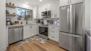 a kitchen with white cabinets and a stainless steel refrigerator at Arrowleaf Family House with Hot Tub in Kanab