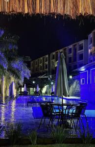 a table with an umbrella on a patio at night at Flat no Condomínio Alto da Serra Villas in Bananeiras