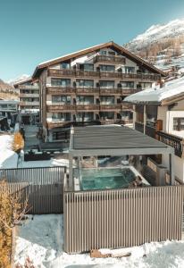 ツェルマットにあるAlpen Resort & Spaの雪中のスイミングプール付きの大きな建物