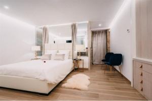 a white bedroom with a white bed and a blue chair at Casa Albarari Boutique Double Rooms with access to shared Infinity Pool in Sanxenxo