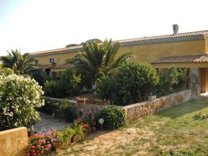 a garden in front of a house with flowers at Agriturismo Lu Colbu in Trinità d'Agultu e Vignola