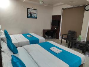 una camera d'albergo con due letti e una scrivania di Hotel Raviraj Palace a Rajkot