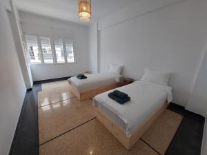 a white room with two beds and a window at Dar Collon in Tangier
