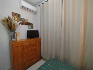 a room with a television on a dresser and a curtain at GuriHouseUai in São Mateus
