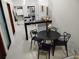 a dining room with a table and chairs and a kitchen at GuriHouseUai in São Mateus
