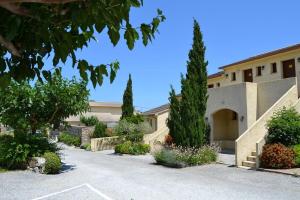 a building with trees and bushes in front of a driveway at Appartement confort et équipé proche de la plage in Sisco