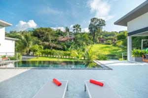 a swimming pool with two lounge chairs in front of a house at Bai Saho Villa 4br - Private Pool & Walk To Beach in Mae Nam