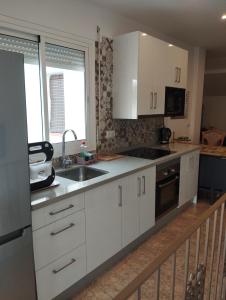 a kitchen with white cabinets and a sink at El ático de la Cañada in Frigiliana