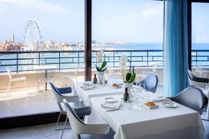 a restaurant with tables and chairs and a view of the ocean at JR Hotels Bari Grande Albergo delle Nazioni in Bari