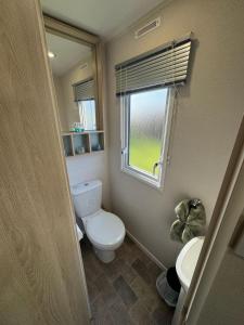 un piccolo bagno con servizi igienici e finestra di Meadowside Caravan Hire Haven Kent Coast ad Allhallows