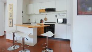 eine Küche mit weißen Schränken, einer Theke und Stühlen in der Unterkunft Regina Nuova 13 in Laglio