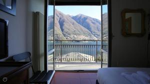 ein Schlafzimmer mit Blick auf einen Balkon mit Bergen in der Unterkunft Regina Nuova 13 in Laglio