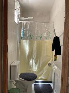 a bathroom with a toilet and a shower curtain at Vila Flor in Cairu