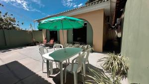 a table and chairs with a green umbrella on a patio at Casa Ribeiro Suíte Novissíma in Boa Vista