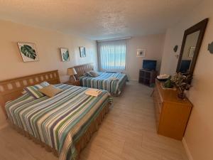 a hotel room with two beds and a television at Oceanfront condo, ocean view and indoor pool in Virginia Beach +28 photos