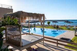 a swimming pool next to the ocean with a resort at Silver Sun Studios & Apartments in Malia