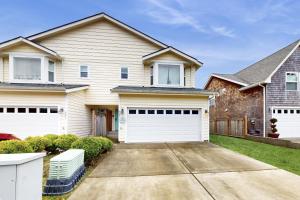 a house with white garage doors in a yard at Lighthouse By The Cove in Seaside