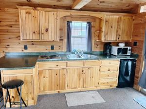 een keuken met houten kasten, een wastafel en een magnetron bij Deluxe Cabin7 Within Campground in Mifflinburg