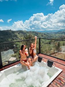 Dos mujeres sentadas en una bañera en una terraza en Cabañas para parejas cerca a Medellín - LUUM By Roots Rentals, en Marinilla