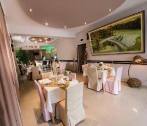 uma sala de jantar com mesas e cadeiras brancas em Hotel Garni Ideal em Podgorica