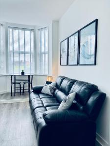 a black leather couch in a living room with a table at Spanish City View 1, Stylish Sea Front Apartment Free Onsite Parking in Whitley Bay