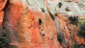 Dos personas caminan por la pared de un cañón. en Kanab Stunning New Deluxe Family Condo Sleeps 10, en Kanab