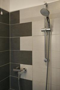 y baño con ducha y azulejos negros y marrones. en B&B Il Sasso Antico, en Verona