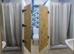 a bathroom with a toilet with two open doors at Backpackers La Gaditana in Alhaurín el Grande +45 photos