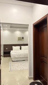 a bedroom with a bed with white sheets and a door at مسكن ركاز المدن in Al Madinah