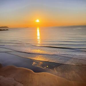 un tramonto sulla spiaggia con il sole che riflette nell'acqua di Uma estadia Sobre as Ondas a Guarujá Altre 64 foto