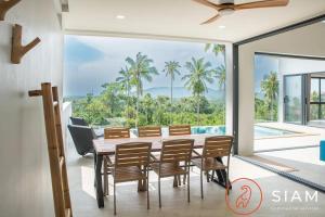 ein Esszimmer mit Tisch und Stühlen und einem großen Fenster in der Unterkunft Villa Toi&Moi 3Br Private Pool Sea View in Ban Thung