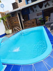 a large blue swimming pool with a tile floor and a house at Pousada Helena in Penha