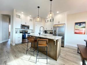 a kitchen with white cabinets and a large island with two bar stools at Southern Utah High Desert Family Home with Private Hot Tub in Kanab