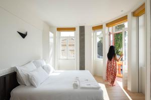 a woman standing in a bedroom looking out the window at A'Mar by Alojamento Ideal in Póvoa de Varzim