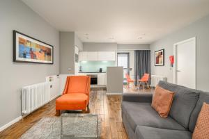 a living room with a couch and an orange chair at Destiny Scotland -The Malt House Apartments in Edinburgh