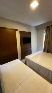 une chambre d'hôtel avec deux lits et une télévision dans l'établissement Apartamento no Barretos Country Resort, à Barretos 4 autres photos
