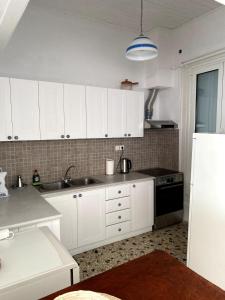 a kitchen with white cabinets and a sink and a refrigerator at House with marina view in Plomari +8 photos