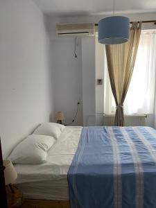 a bedroom with a bed with a blue blanket and a window at House with marina view in Plomari