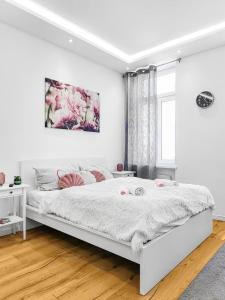 1 dormitorio blanco con 1 cama blanca grande con almohadas rosas en Nordwestbahn Apartments, en Viena