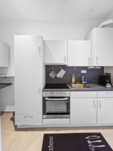 cocina con armarios blancos y horno de acero inoxidable en Nordwestbahn Apartments, en Viena